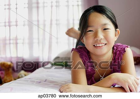 Girl in bedroom, lying on bed, looking at camera View Large Photo Image Stock Image - Girl in bedroom, lying on bed, looking at camera . Fotosearch