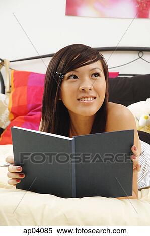 Girl lying on bed, holding diary, looking away View Large Photo Image Stock Photography - Girl lying on bed, holding diary, looking away . Fotosearch