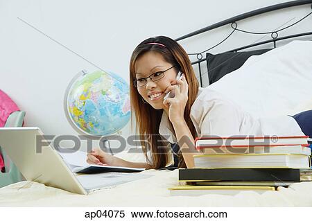 Girl lying on bed, using laptop and mobile phone View Large Photo Image Stock Photography - Girl lying on bed, using laptop and mobile phone . Fotosearch