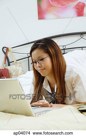 Girl lying on bed, using laptop View Large Photo Image Picture - Girl lying on bed, using laptop. Fotosearch