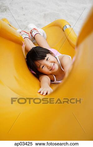 Girl on slide, smiling up at camera, high angle view View Large Photo Image Stock Photography - Girl on slide, smiling up at camera, high angle view . Fotosearch