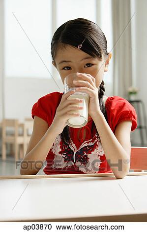 Girl sitting at table, drinking glass of milk View Large Photo Image Stock Image - Girl sitting at table, drinking glass of milk . Fotosearch
