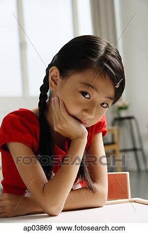 Girl sitting at table, looking at camera, hand on chin View Large Photo Image Stock Photo - Girl sitting at table, looking at camera, hand on chin . Fotosearch
