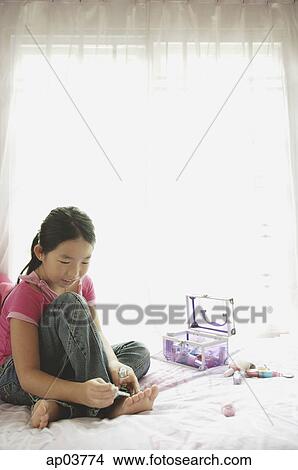 Girl sitting on bed, painting toenails View Large Photo Image Picture - Girl sitting on bed, painting toenails . Fotosearch