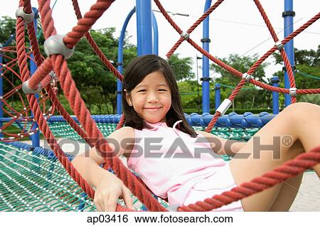 Stock Photograph - Girl sitting on jungle gym, smiling at camera . Fotosearch