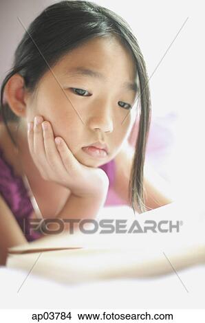 Girl with hand on chin, looking at book View Large Photo Image Picture - Girl with hand on chin, looking at book. Fotosearch