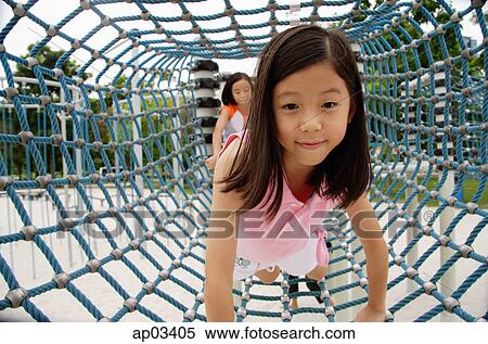 Stock Photography - Girls at playground, going through net tunnel. Fotosearch