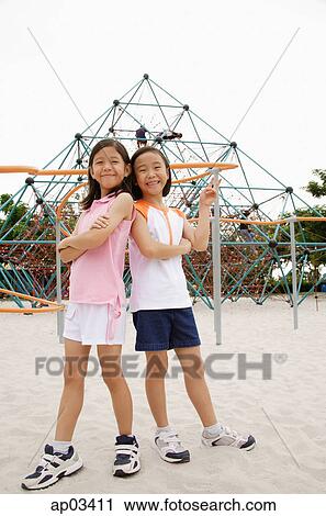 Girls at playground, standing back to back, smiling at camera View Large Photo Image Stock Image - Girls at playground, standing back to back, smiling at camera. Fotosearch