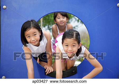 Stock Photo - Girls in playground, climbing through a hole. Fotosearch
