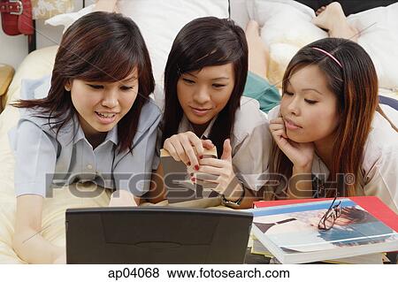 Girls in school uniform lying side by side on bed, reading book View Large Photo Image Stock Photo - Girls in school uniform lying side by side on bed, reading book . Fotosearch