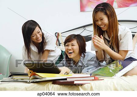 Girls in school uniform, side by side on bed, laughing View Large Photo Image Picture - Girls in school uniform, side by side on bed, laughing. Fotosearch