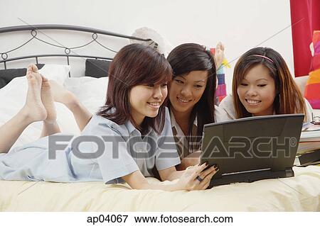 Girls in school uniform, side by side on bed, reading book View Large Photo Image Stock Photo - Girls in school uniform, side by side on bed, reading book . Fotosearch
