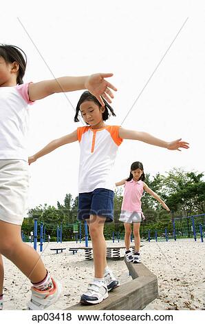 Stock Photo - Girls walking on balance beams, arms outstretched . Fotosearch