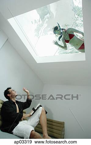 Man in living room, waving at woman in swimming pool through the skylight View Large Photo Image Stock Photo - Man in living room, waving at woman in swimming pool through the skylight. Fotosearch