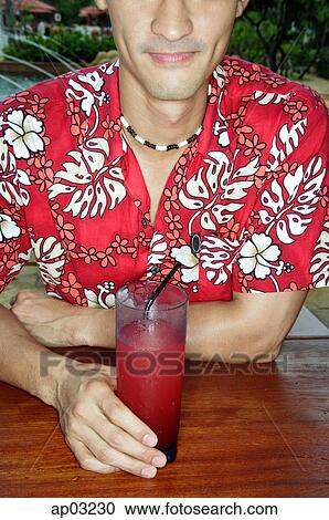 Stock Image - Man sitting at bar counter, holding drink. Fotosearch