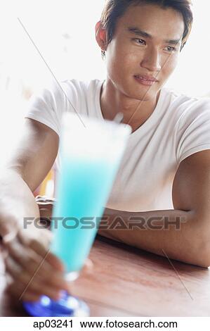Man sitting at table, holding drink, selective focus View Large Photo Image Stock Image - Man sitting at table, holding drink, selective focus . Fotosearch