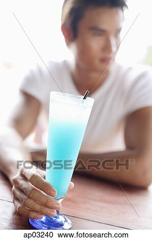 Stock Image - Man with drink, looking away, selective focus . Fotosearch