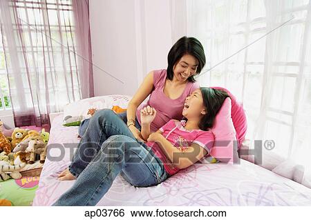 Mother tickling daughter in bedroom View Large Photo Image Stock Photograph - Mother tickling daughter in bedroom. Fotosearch