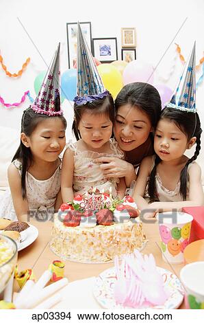 Mother with three daughters celebrating a birthday, looking at cake View Large Photo Image Picture - Mother with three daughters celebrating a birthday, looking at cake . Fotosearch