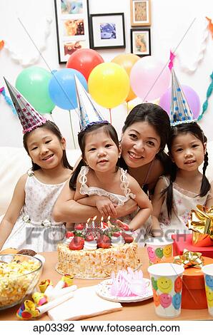 Stock Image - Mother with three girls celebrating a birthday . Fotosearch