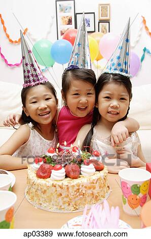 Stock Photo - Three girls celebrating a birthday, smiling at camera. Fotosearch