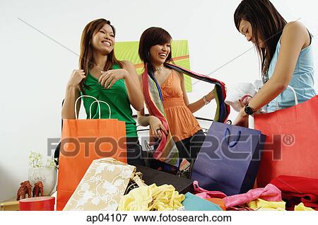 Three girls in bedroom, looking at clothes from shopping bags View Large Photo Image Stock Photo - Three girls in bedroom, looking at clothes from shopping bags . Fotosearch