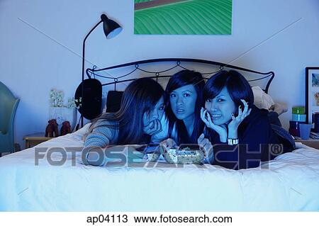 Three girls in bedroom, lying on bed, watching TV View Large Photo Image Stock Image - Three girls in bedroom, lying on bed, watching TV. Fotosearch