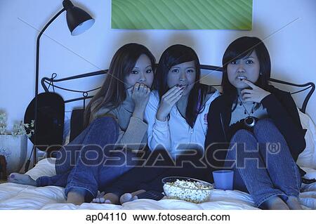 Three girls in bedroom, watching TV and eating popcorn View Large Photo Image Stock Image - Three girls in bedroom, watching TV and eating popcorn . Fotosearch
