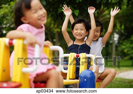 Three girls on a seesaw, arms outstretched View Large Photo Image Picture - Three girls on a seesaw, arms outstretched . Fotosearch