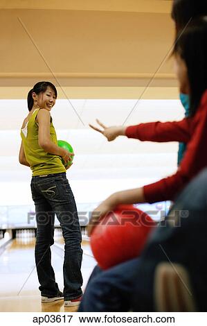 Stock Photo - Three women at a bowling alley, one woman with bowling ball, looking over shoulder. Fotosearch