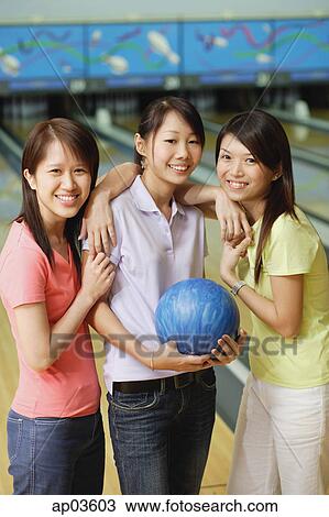 Three women at bowling alley, standing side by side, smiling at camera View Large Photo Image Stock Image - Three women at bowling alley, standing side by side, smiling at camera. Fotosearch