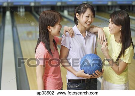 Stock Image - Three women at bowling alley, talking . Fotosearch