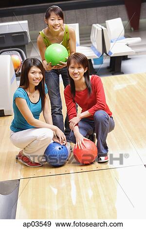 Three women in bowling alley, with bowling balls, smiling at camera View Large Photo Image Stock Photo - Three women in bowling alley, with bowling balls, smiling at camera . Fotosearch