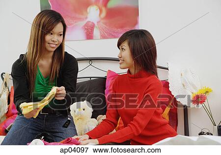 Two girls in bedroom, one holding folded clothes View Large Photo Image Stock Photo - Two girls in bedroom, one holding folded clothes . Fotosearch