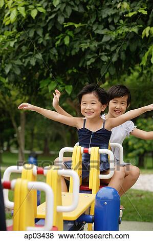 Stock Photo - Two girls on a seesaw, arms outstretched . Fotosearch