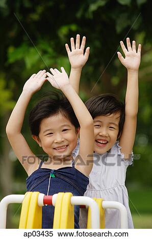Stock Photography - Two girls on a seesaw, arms outstretched . Fotosearch