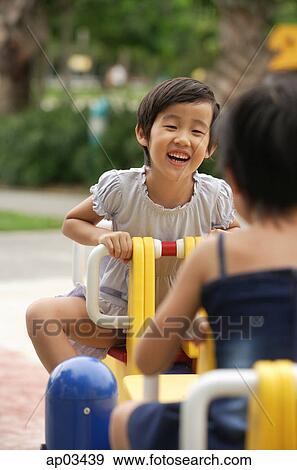 Two girls on a seesaw, face to face View Large Photo Image Stock Photo - Two girls on a seesaw, face to face. Fotosearch