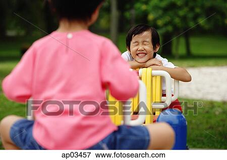 Two girls on a seesaw, one leaning on arms, smiling, eyes closed View Large Photo Image Stock Photo - Two girls on a seesaw, one leaning on arms, smiling, eyes closed. Fotosearch
