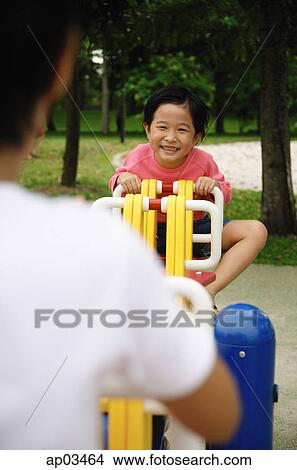 Picture - Two girls on a seesaw, over the shoulder view . Fotosearch