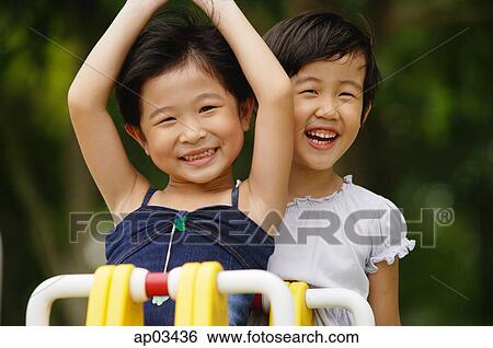 Stock Photograph - Two girls on a seesaw, smiling. Fotosearch