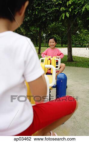 Stock Image - Two girls on a seesaw . Fotosearch