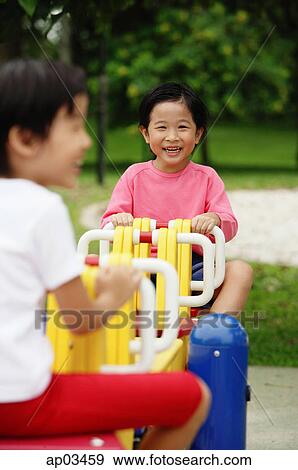 Two girls on a seesaw View Large Photo Image Stock Photo - Two girls on a seesaw . Fotosearch