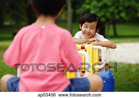 Stock Photograph - Two girls on a seesaw. Fotosearch