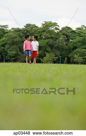 Stock Photo - Two girls on grass, walking, holding hands . Fotosearch