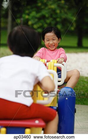Two girls playing on a seesaw View Large Photo Image Stock Image - Two girls playing on a seesaw . Fotosearch