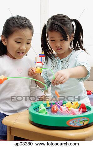 Stock Image - Two girls playing with fishing game . Fotosearch