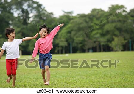 Stock Image - Two girls running on grass, side by side, arms outstretched . Fotosearch