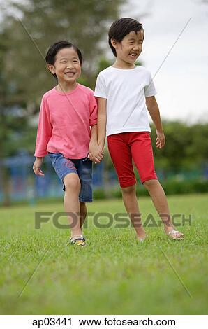 Two girls walking hand in hand in park View Large Photo Image Stock Image - Two girls walking hand in hand in park. Fotosearch