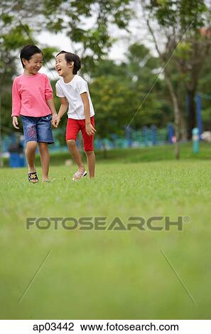 Two girls walking in park, laughing View Large Photo Image Stock Image - Two girls walking in park, laughing . Fotosearch