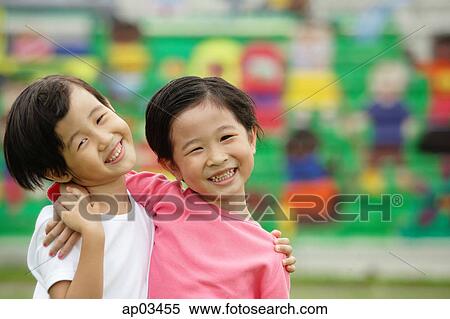 Two girls with arms around each other, smiling at camera View Large Photo Image Stock Photography - Two girls with arms around each other, smiling at camera . Fotosearch